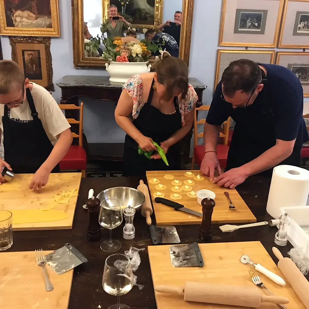 Small group shaping filled pasta around the wooden table