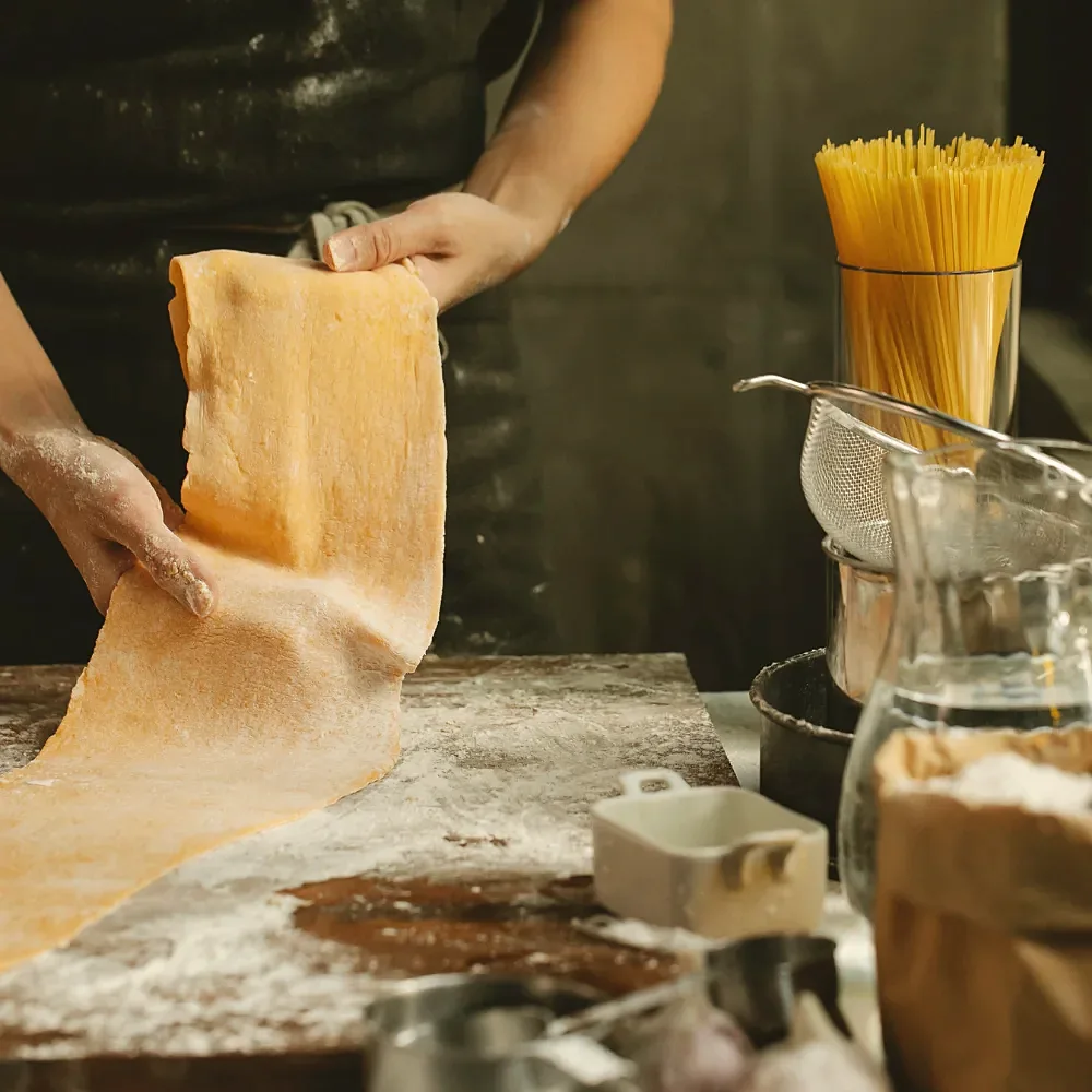 Hands stretching a sheet of fresh pasta