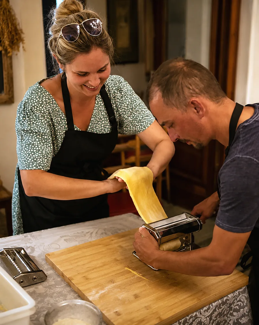 Couple laughing while rolling pasta through the machine